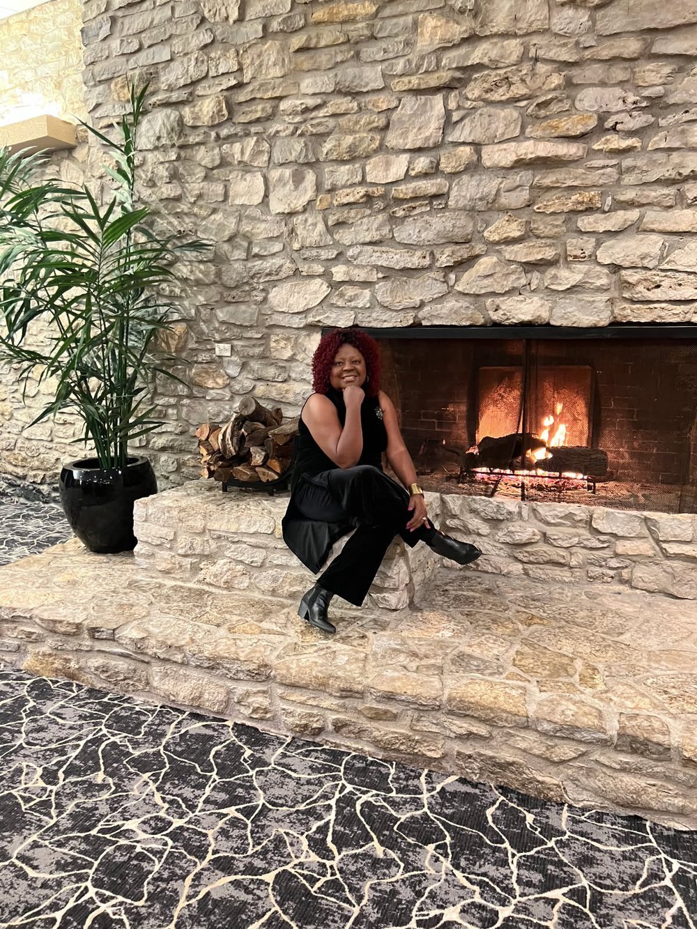 Brenda Murphy seated beside a stone fireplace
